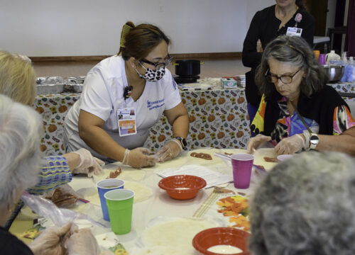 UWF nursing student makes lumpia with a member of the Bayview Senior Resource Center.